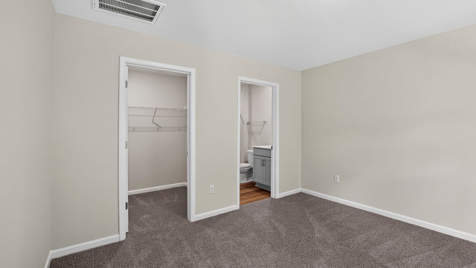 Primary bedroom with carpet and windows.