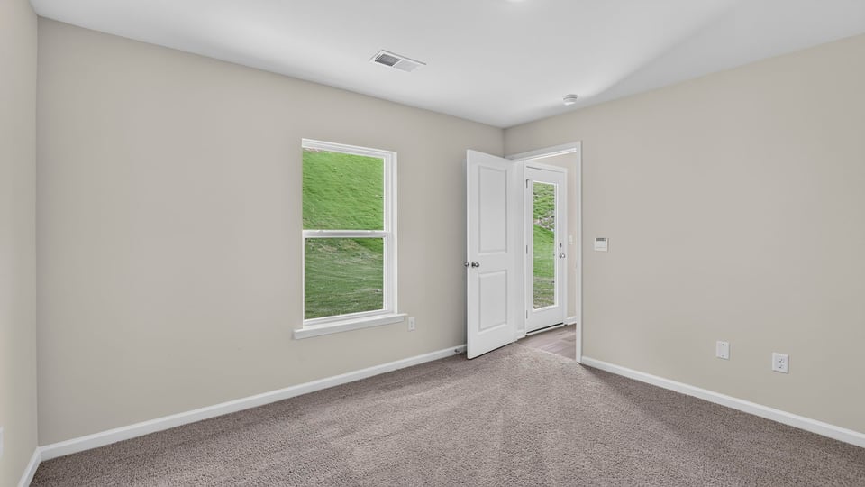 Primary bedroom with carpet and windows.