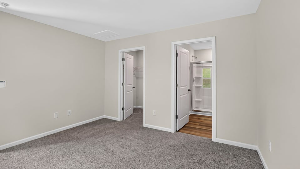 Primary bedroom with carpet and windows.