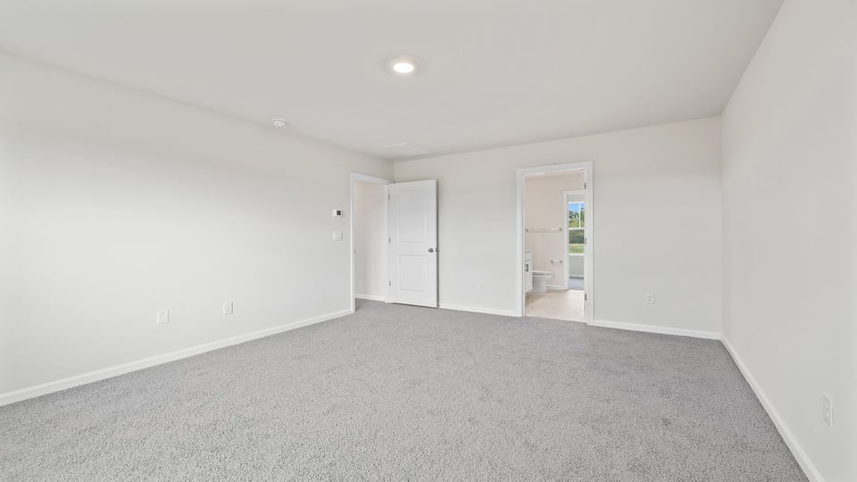 Primary bedroom with window and carpet.