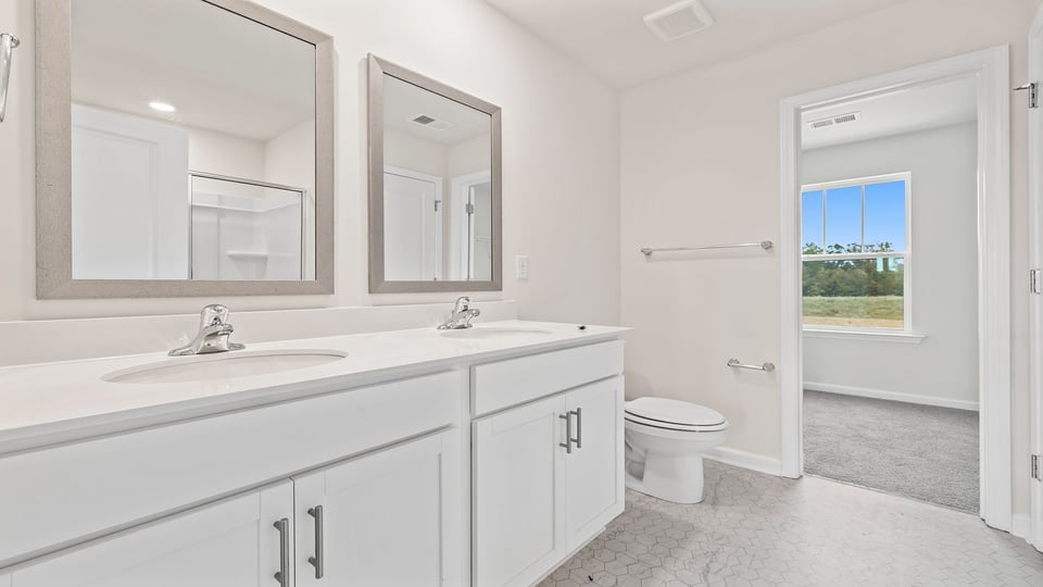 Primary bathroom with dual sink vanity and mirrors.