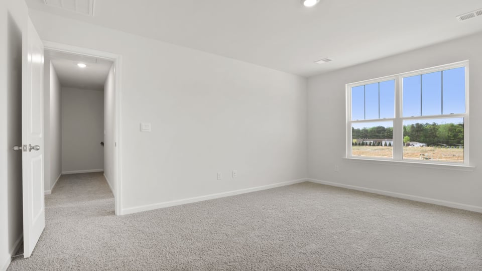 Primary bedroom with carpet and windows.