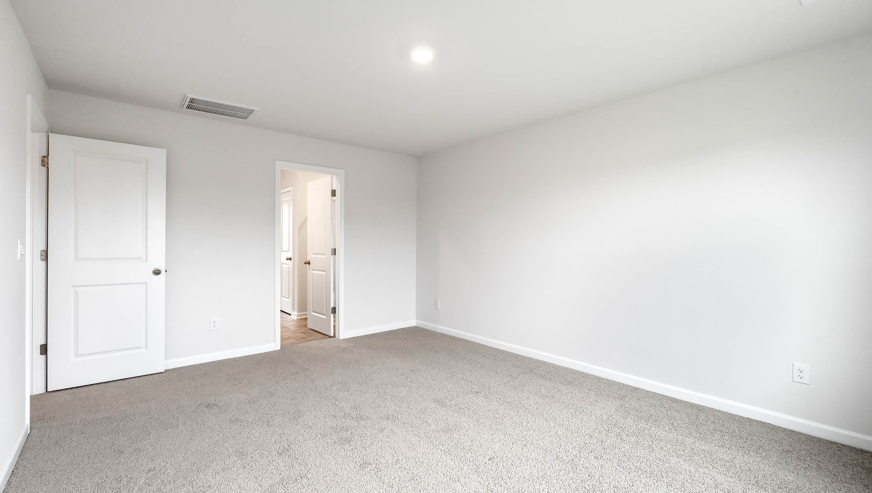 Primary bedroom with carpet and window.