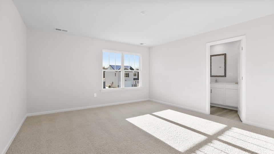 Primary bedroom with carpet and window.