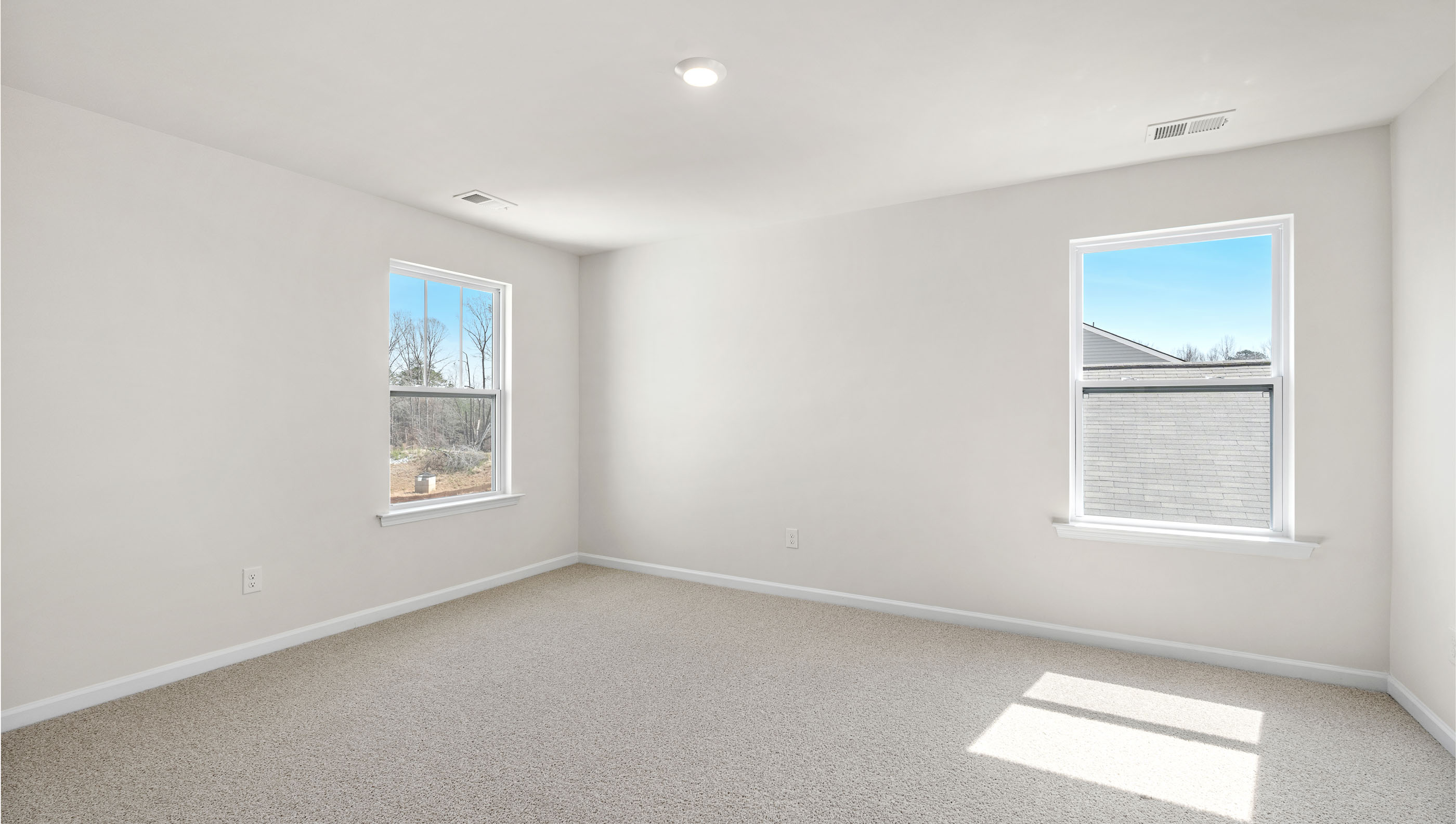 Primary bedroom with carpet and windows.