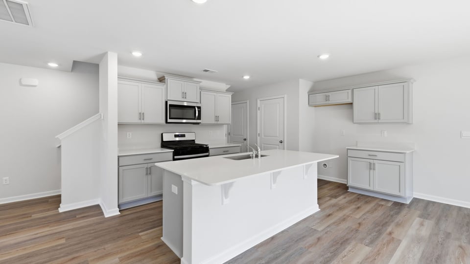 Kitchen and island with quartz countertops and stainless steel appliances.