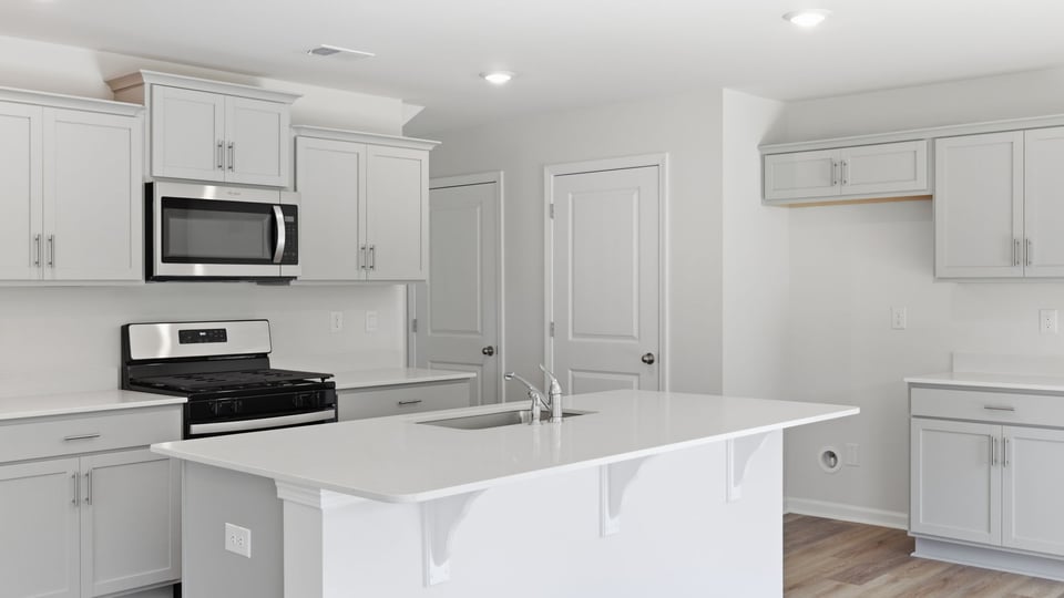 Kitchen and island with quartz countertops and stainless steel appliances.