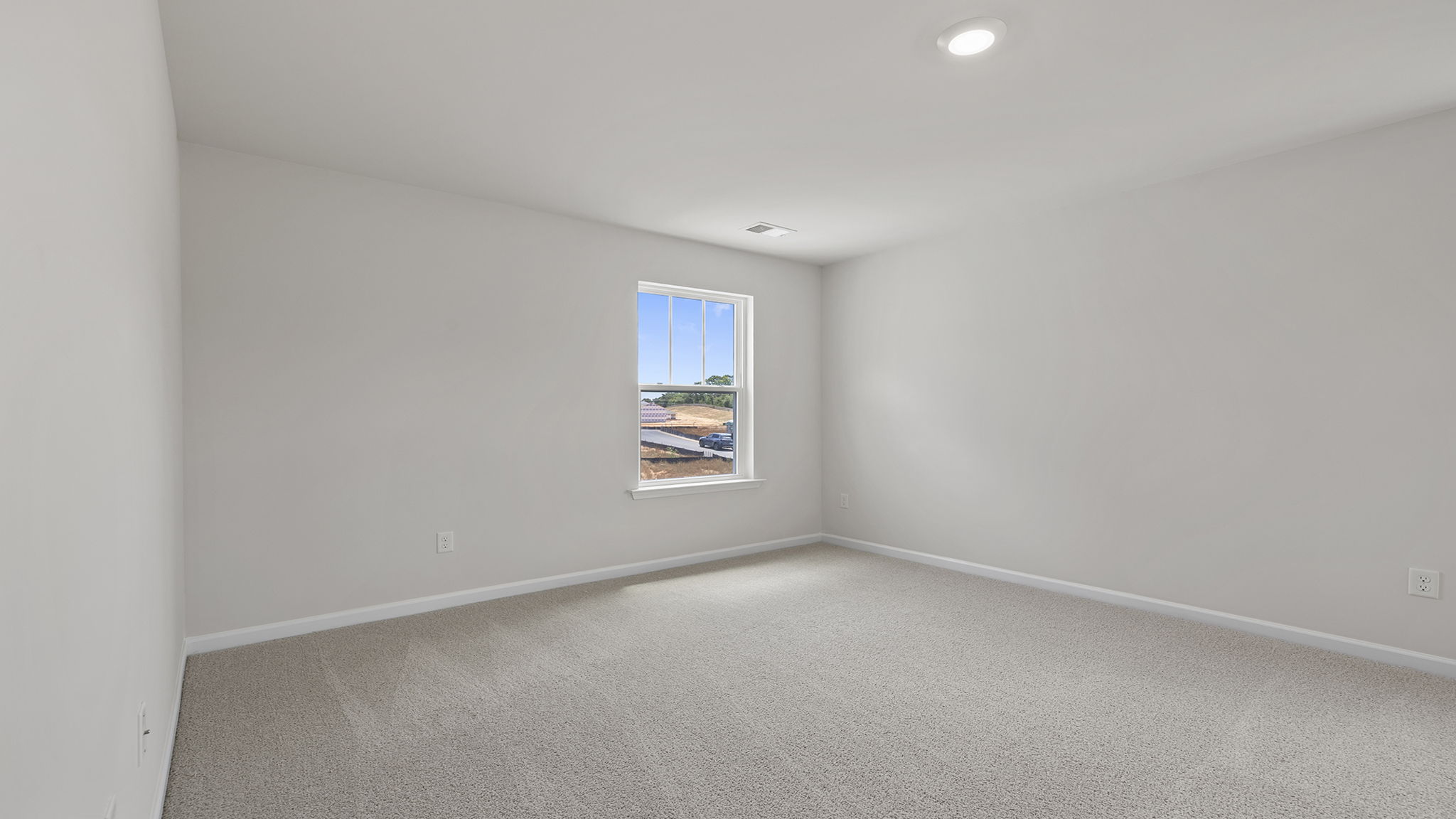 Primary bedroom with carpet and windows.