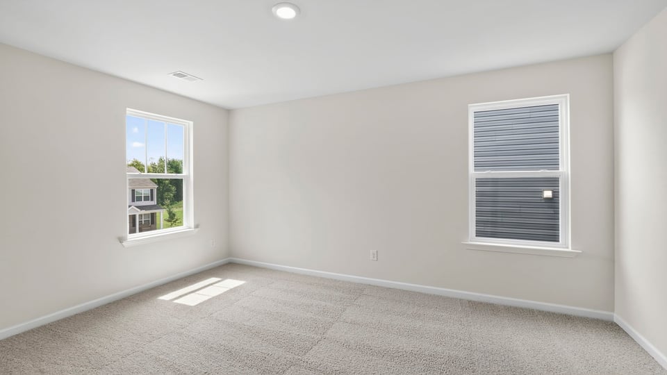 Primary bedroom with carpet and windows.