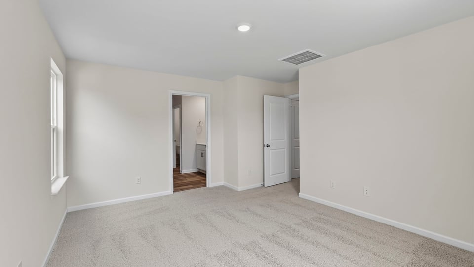 Primary bedroom with carpet and windows.