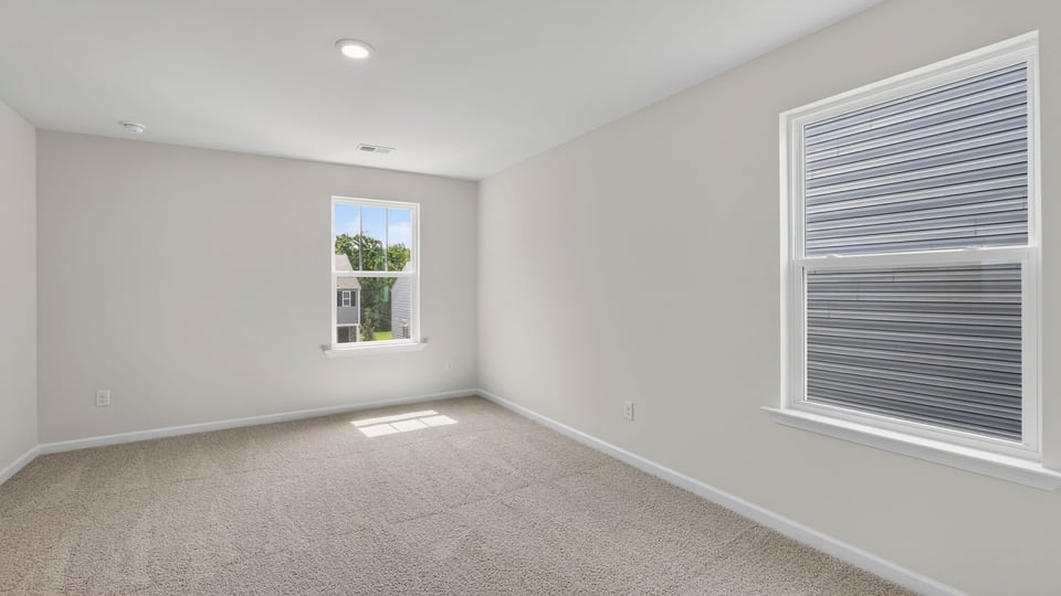 Primary bedroom with carpet and windows.