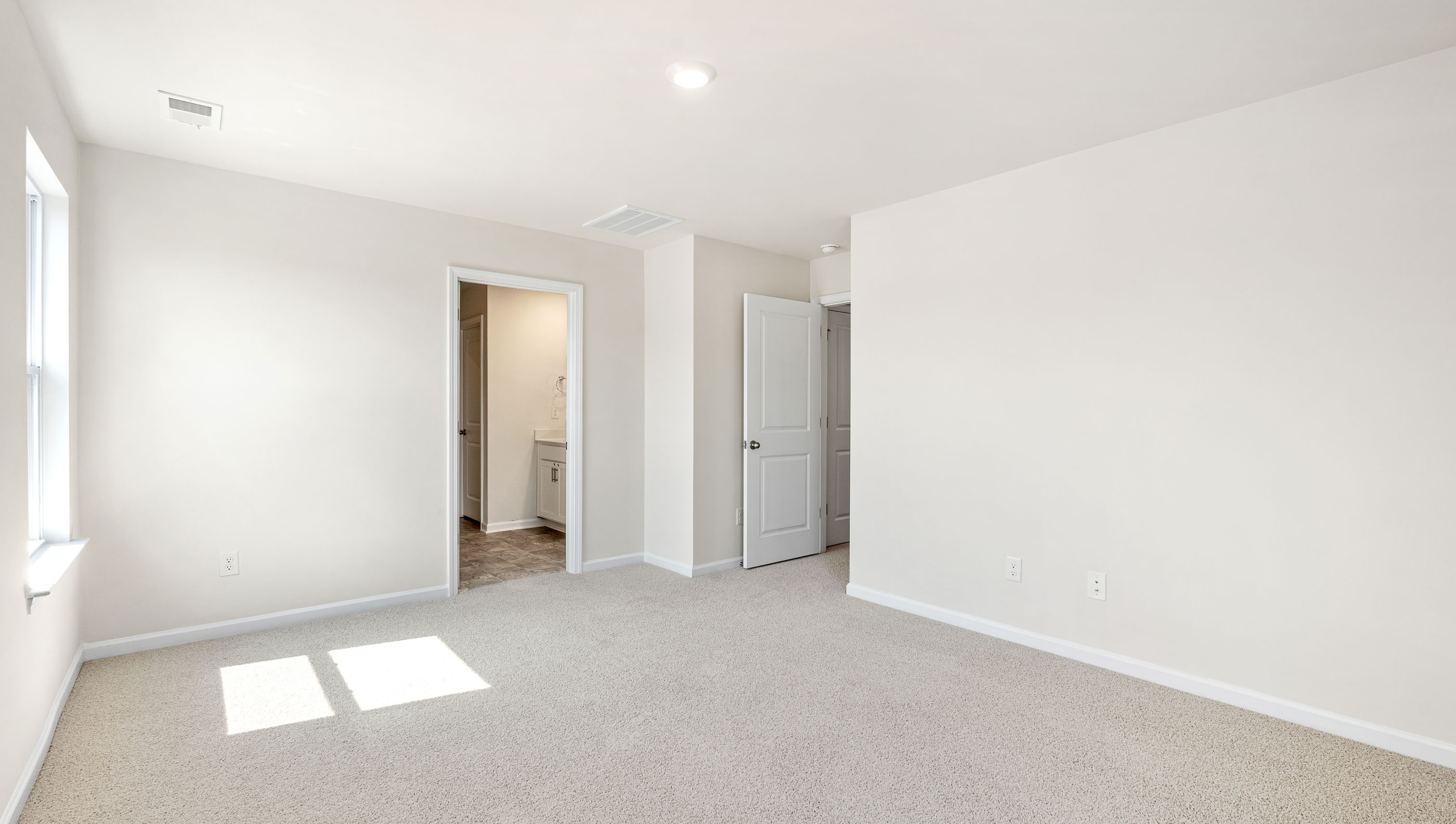 Primary bedroom with carpet and window.