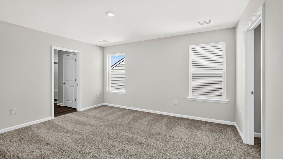 Primary bedroom with carpet and windows.