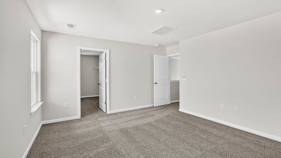 Primary bedroom with carpet and windows.