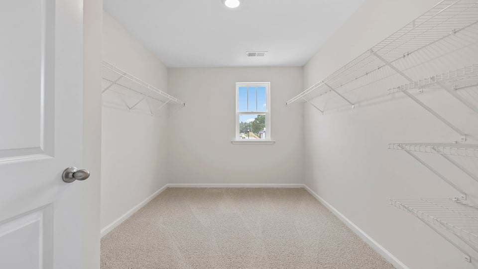 Primary closet with window and carpet.