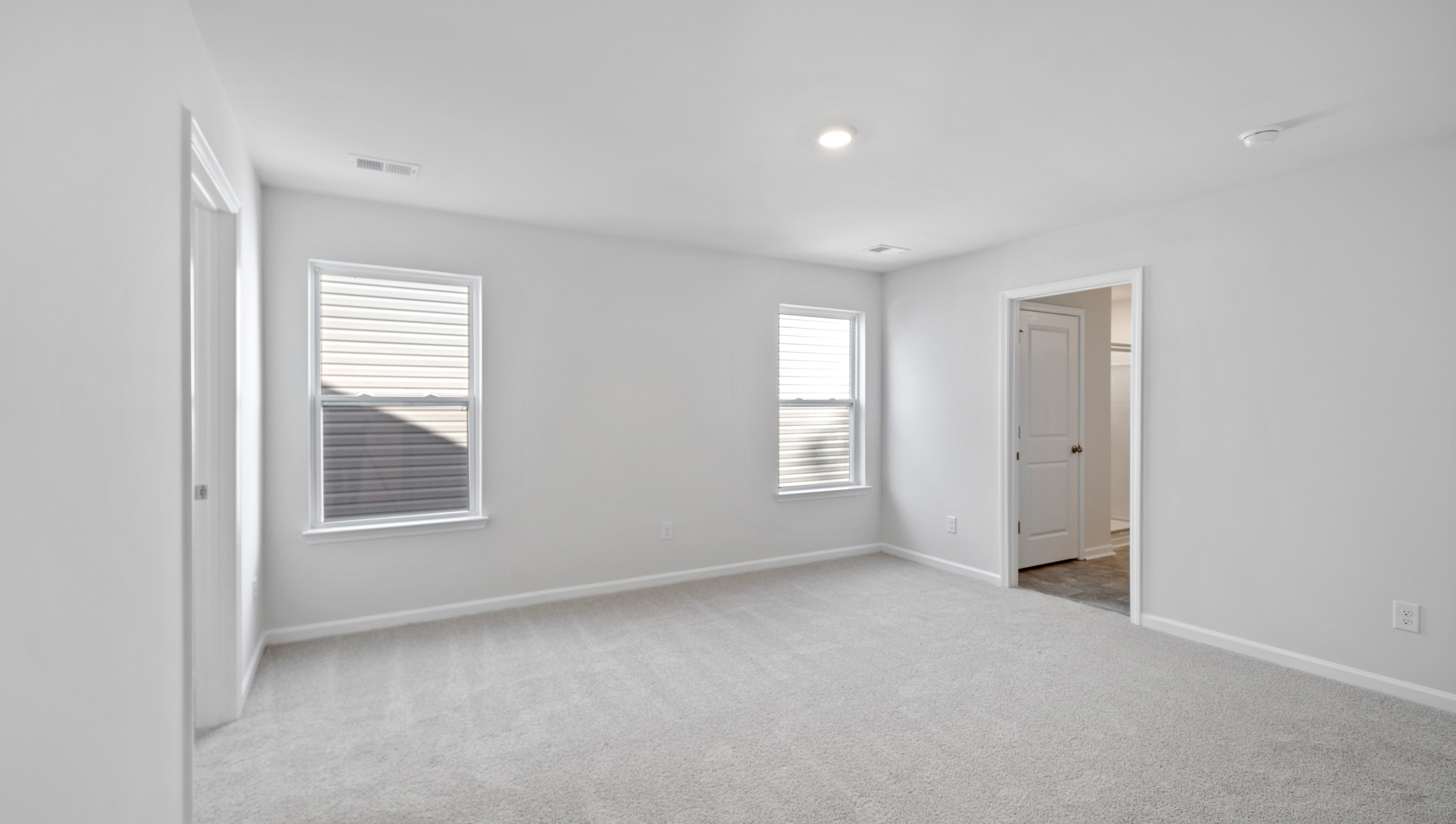 Primary bedroom with carpet and window.