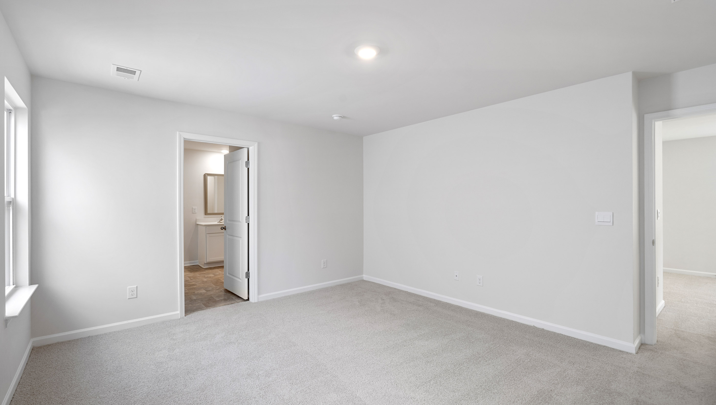 Primary bedroom with carpet and window.