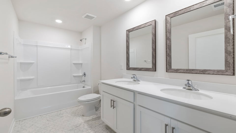 Hall bathroom with dual sink vanity and combination shower / tub.,