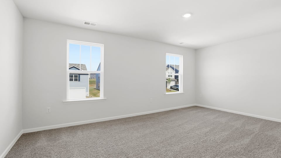 Primary bedroom with carpet and windows.