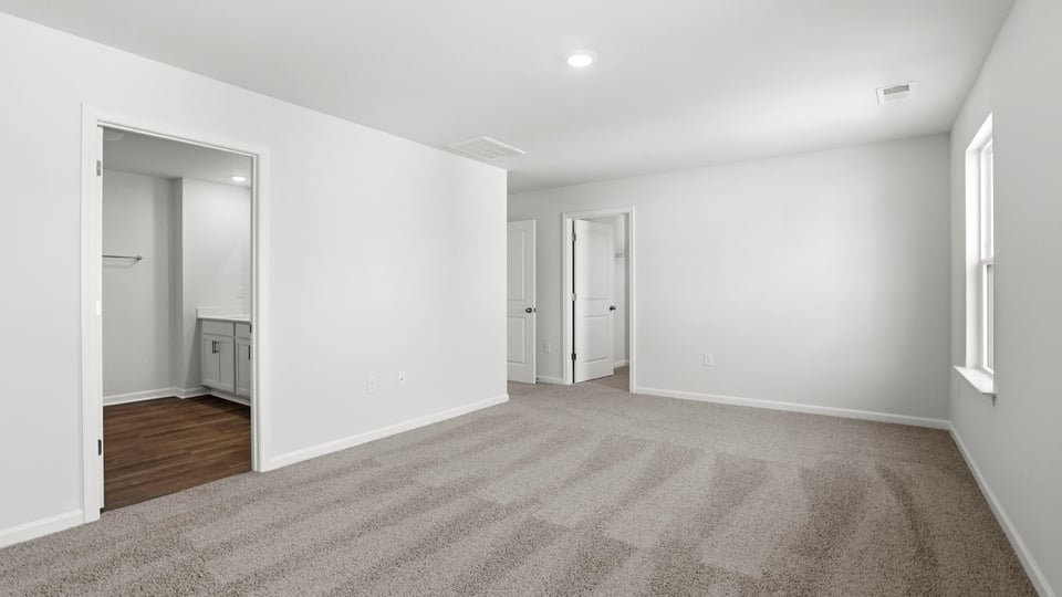Primary bedroom with carpet and windows.