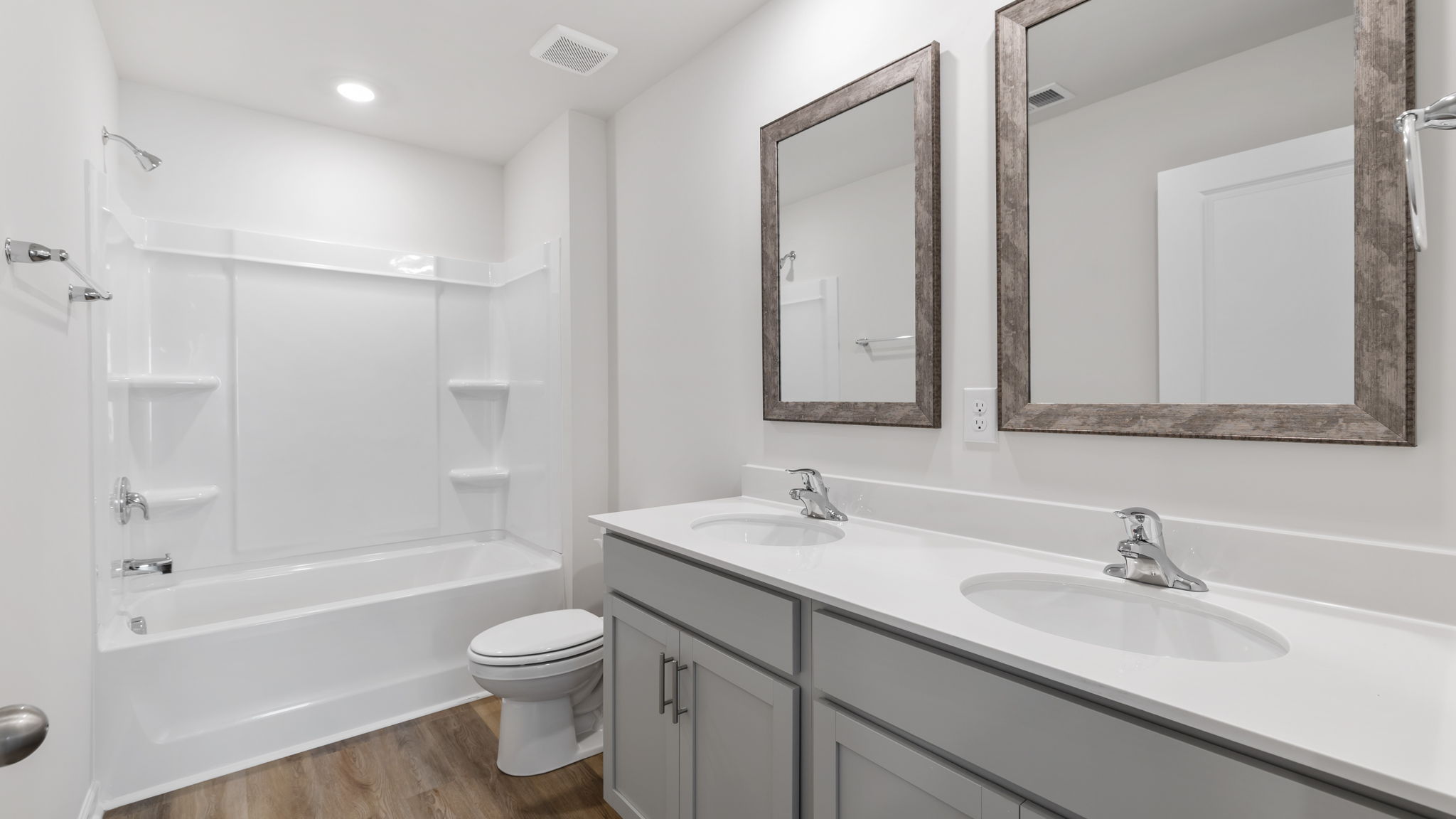 Hall bathroom with dual sink vanity and combination tub / shower.