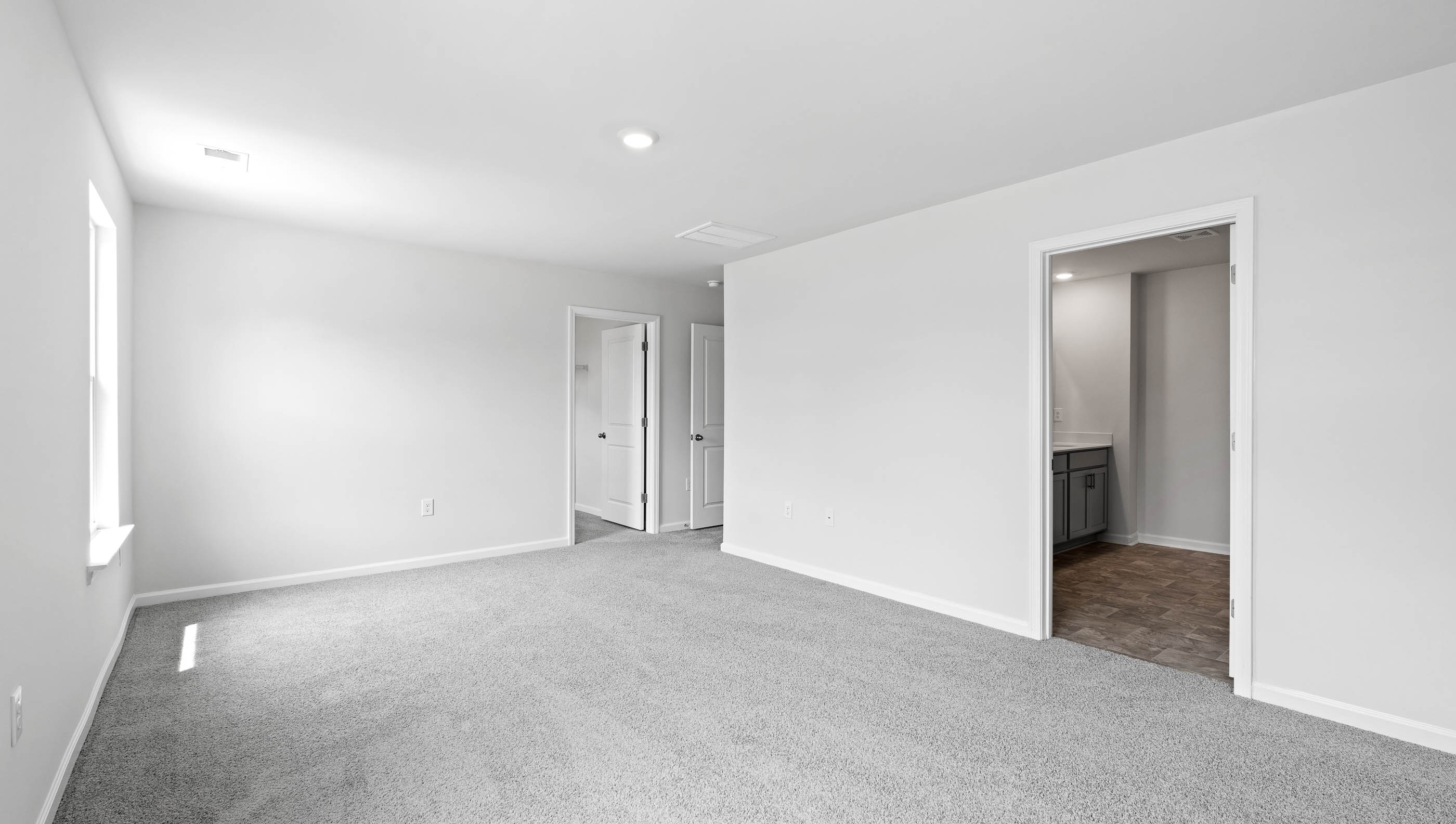 Primary bedroom with carpet and windows.