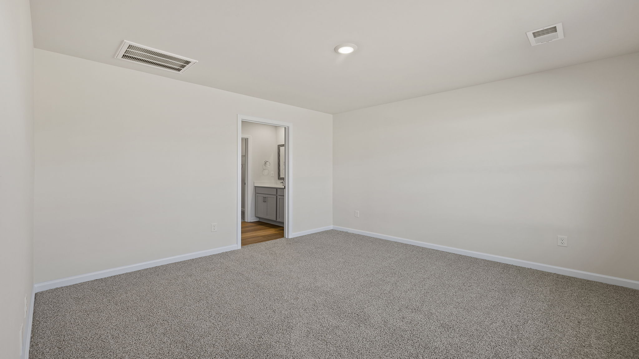 Primary bedroom off the family room with large window and carpet.