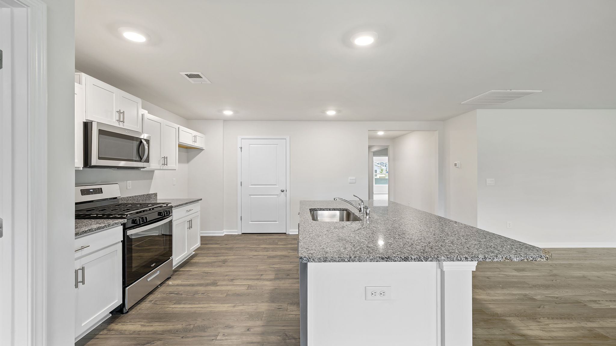 View of kitchen with island and hallway to the entrance.