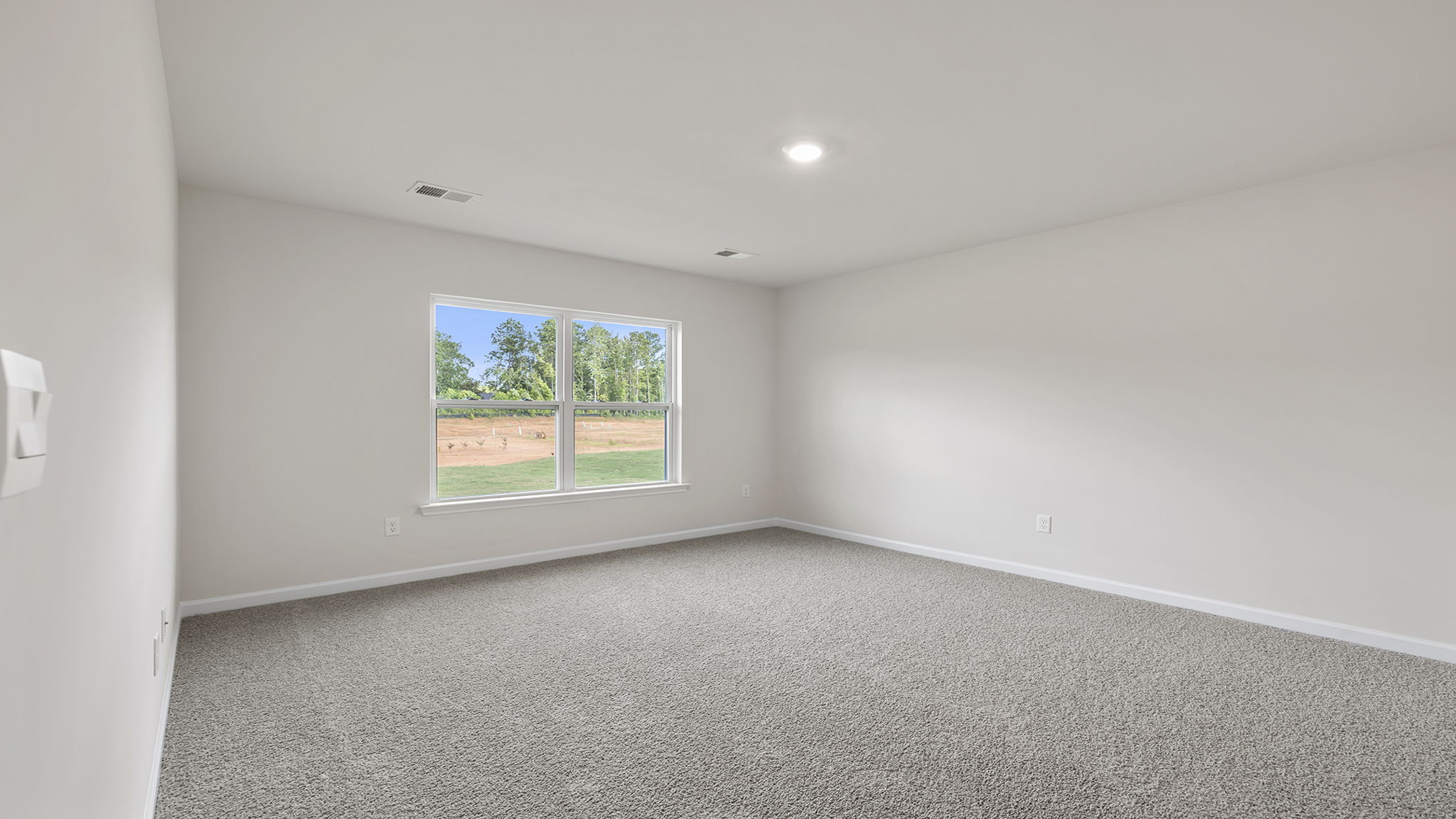 Primary bedroom with carpet and window.