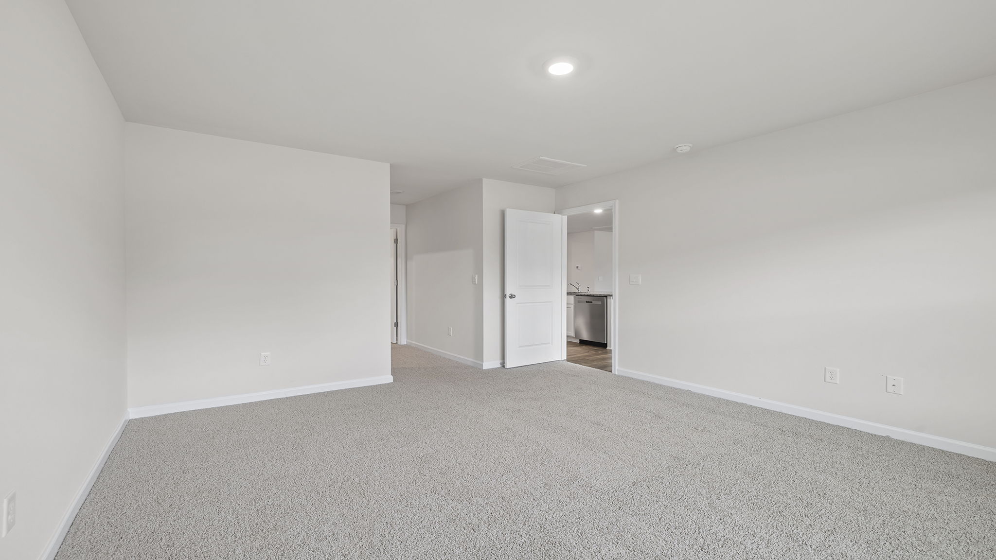 Primary bedroom with carpet and window.