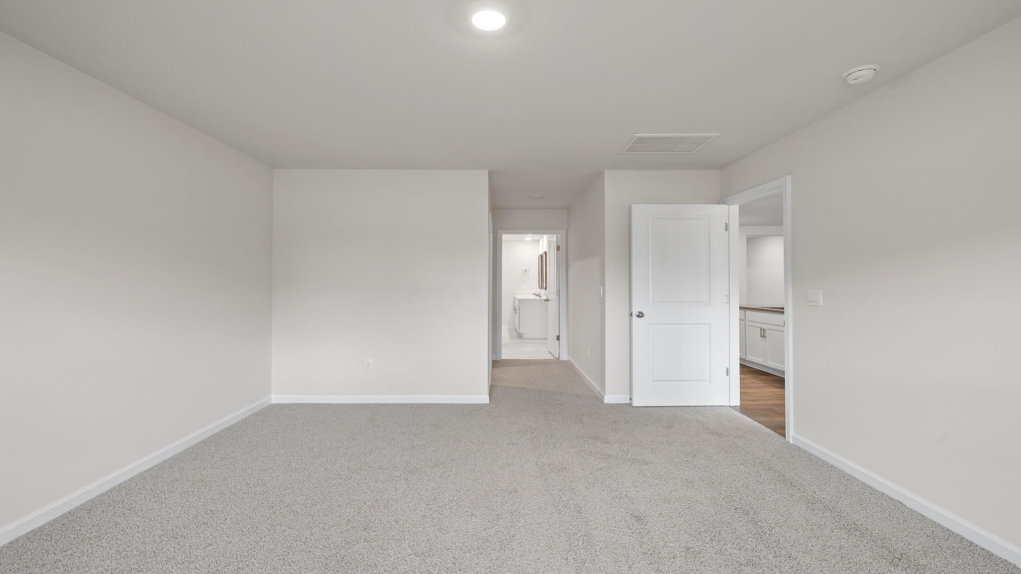 Primary bedroom with carpet and window.