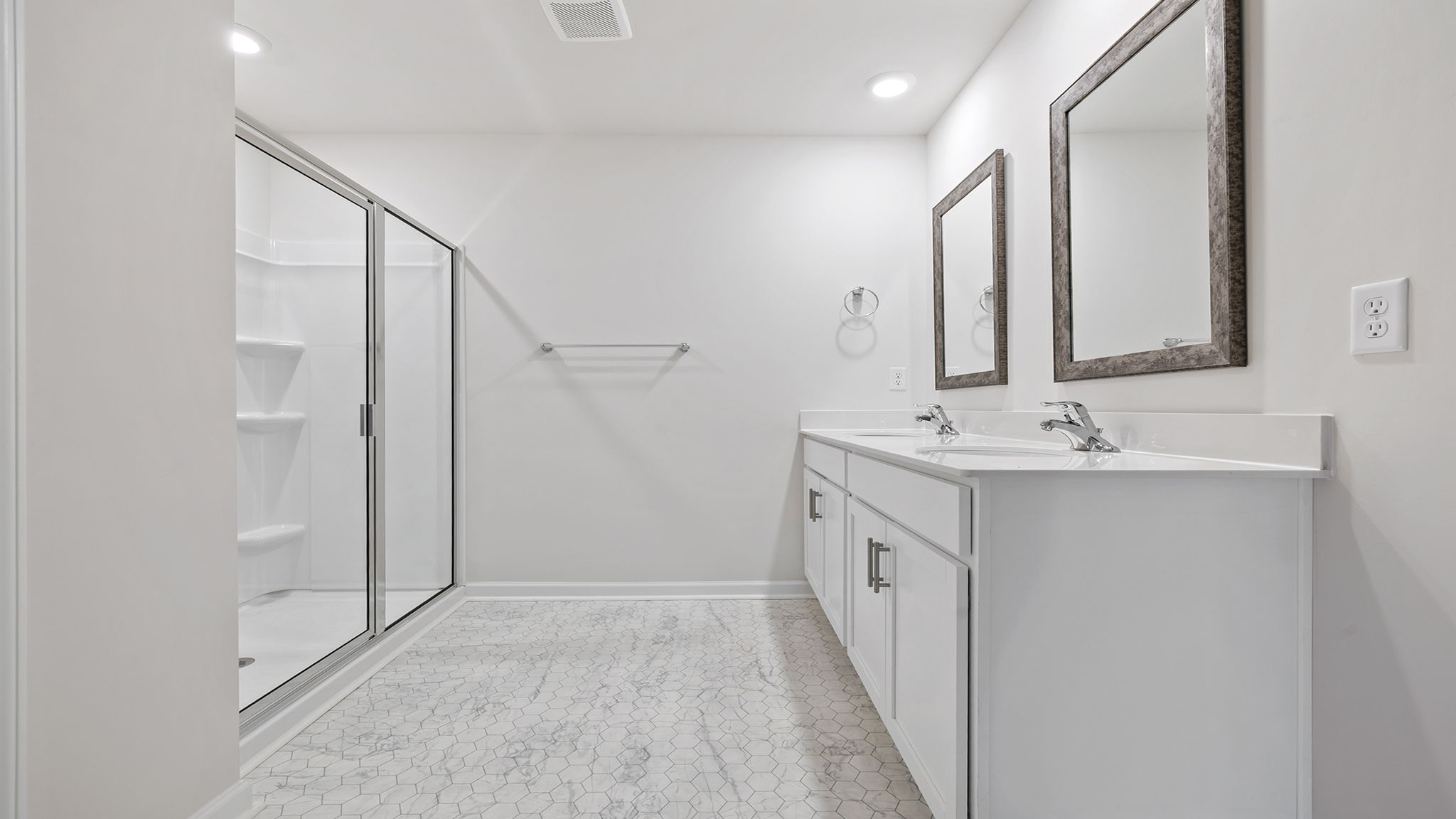 Primary bathroom with dual sink vanity and mirrors and walk-in shower.