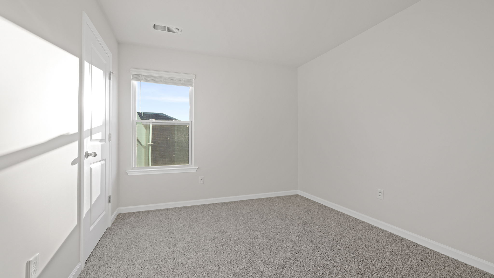 Bedroom with large window and carpet.