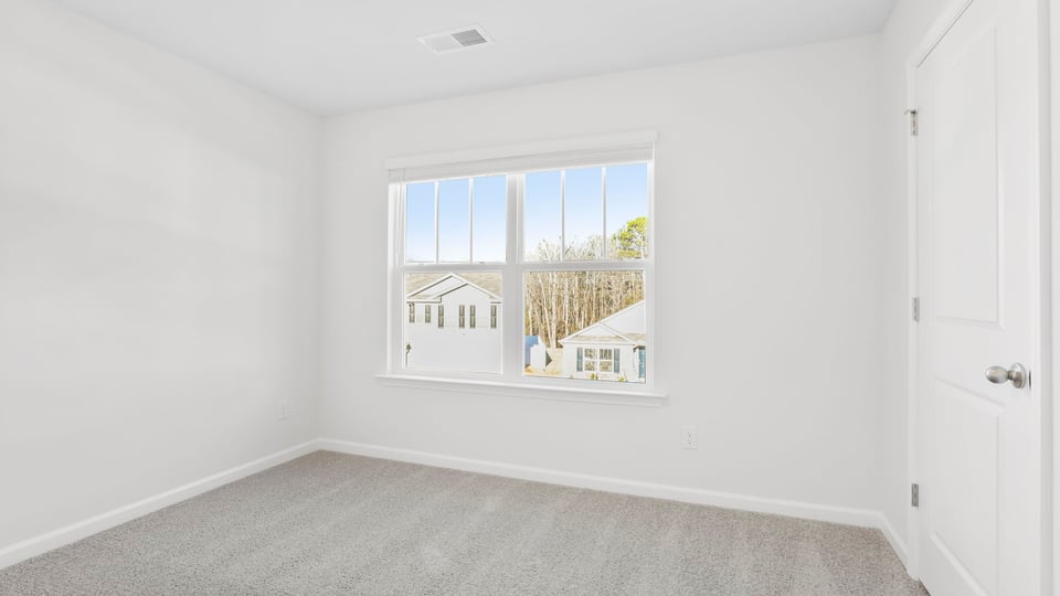 Bedroom with large window and carpet.