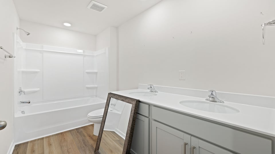Hall bathroom with dual sink vanity and combination shower / tub.