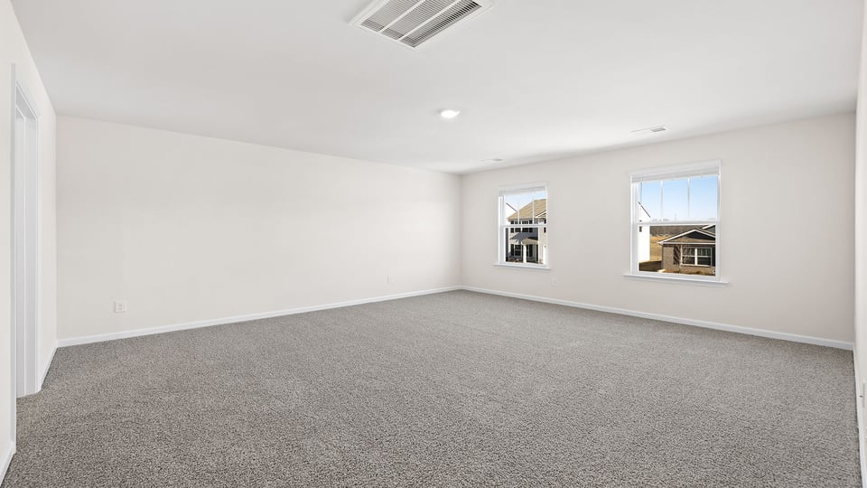 Primary bedroom with carpet and windows.
