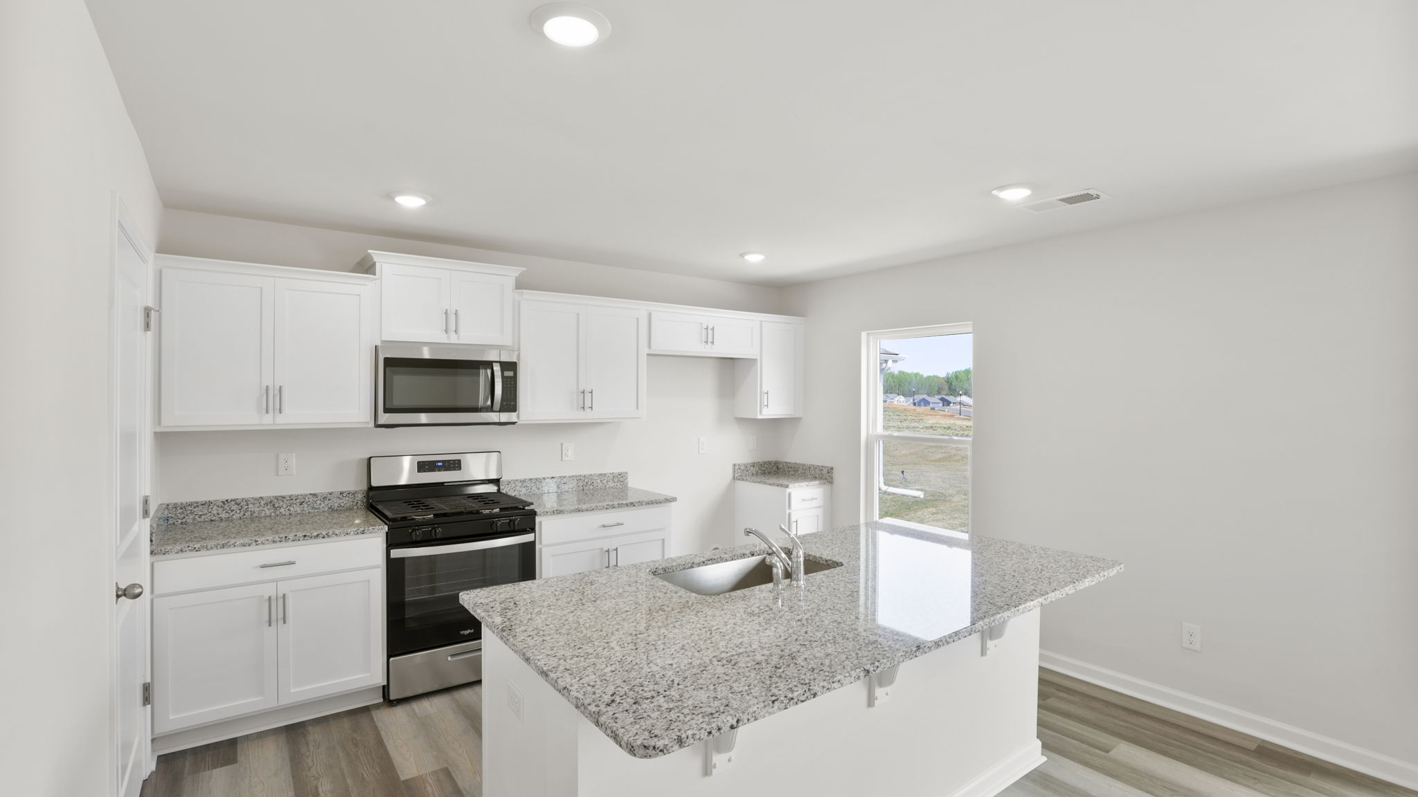Kitchen and island with stainless steel appliances and quartz countertops.