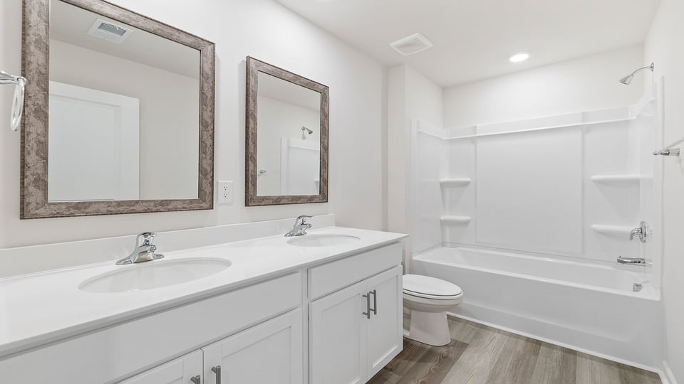 Hall bathroom with dual sink vanity and combination shower / tub.