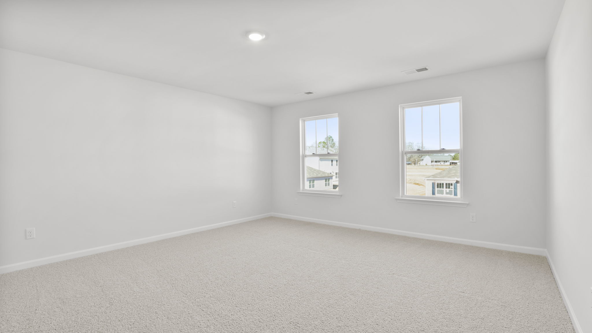 Primary bedroom with carpet and 2 large windows.