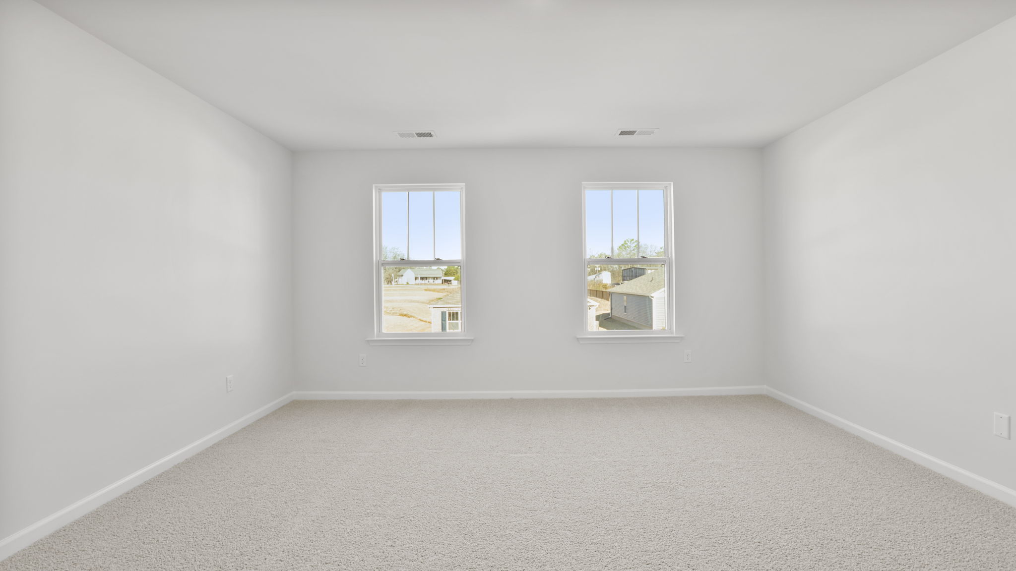Primary bedroom with carpet and 2 large windows.