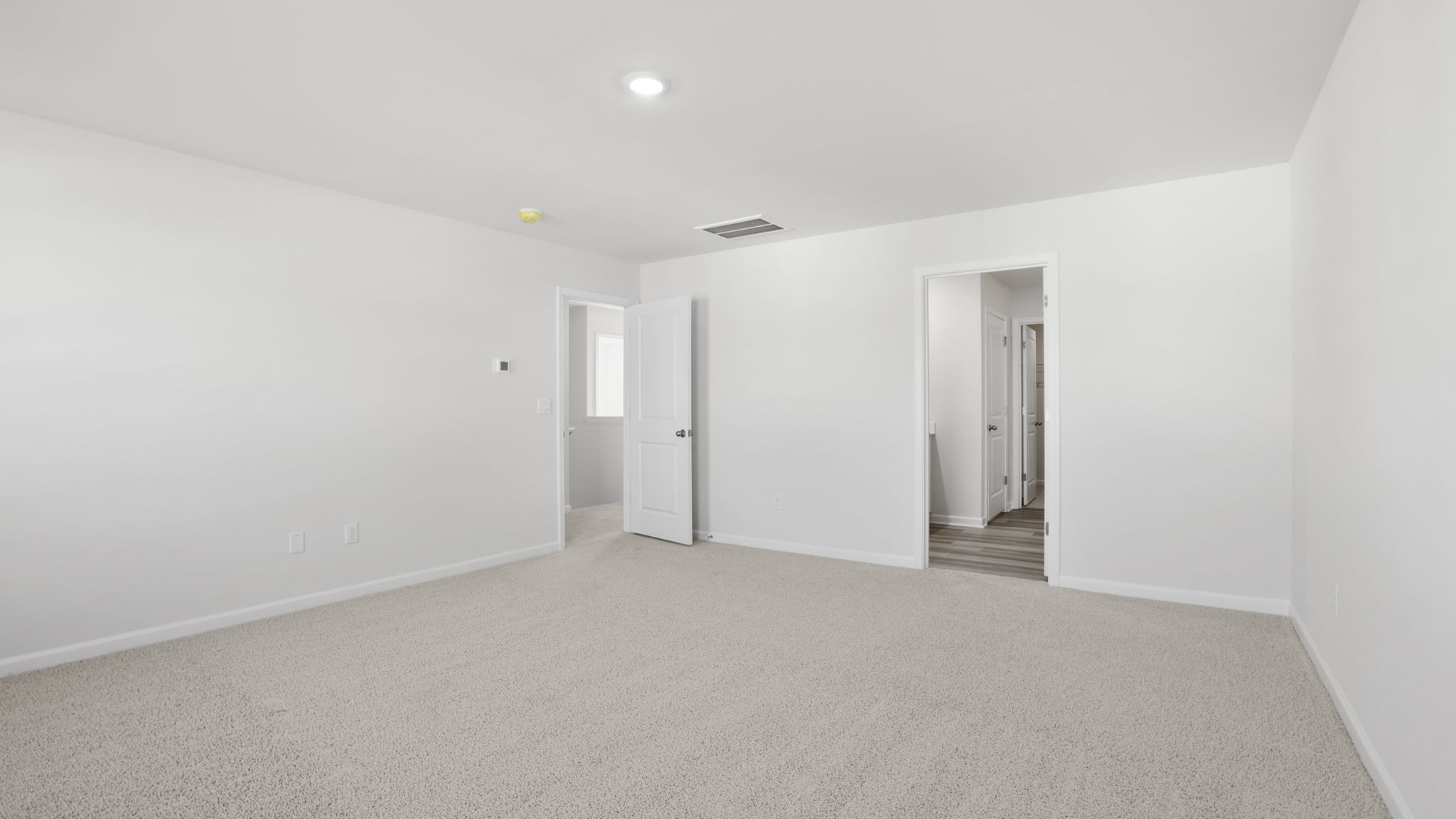 Primary bedroom with carpet and 2 large windows.