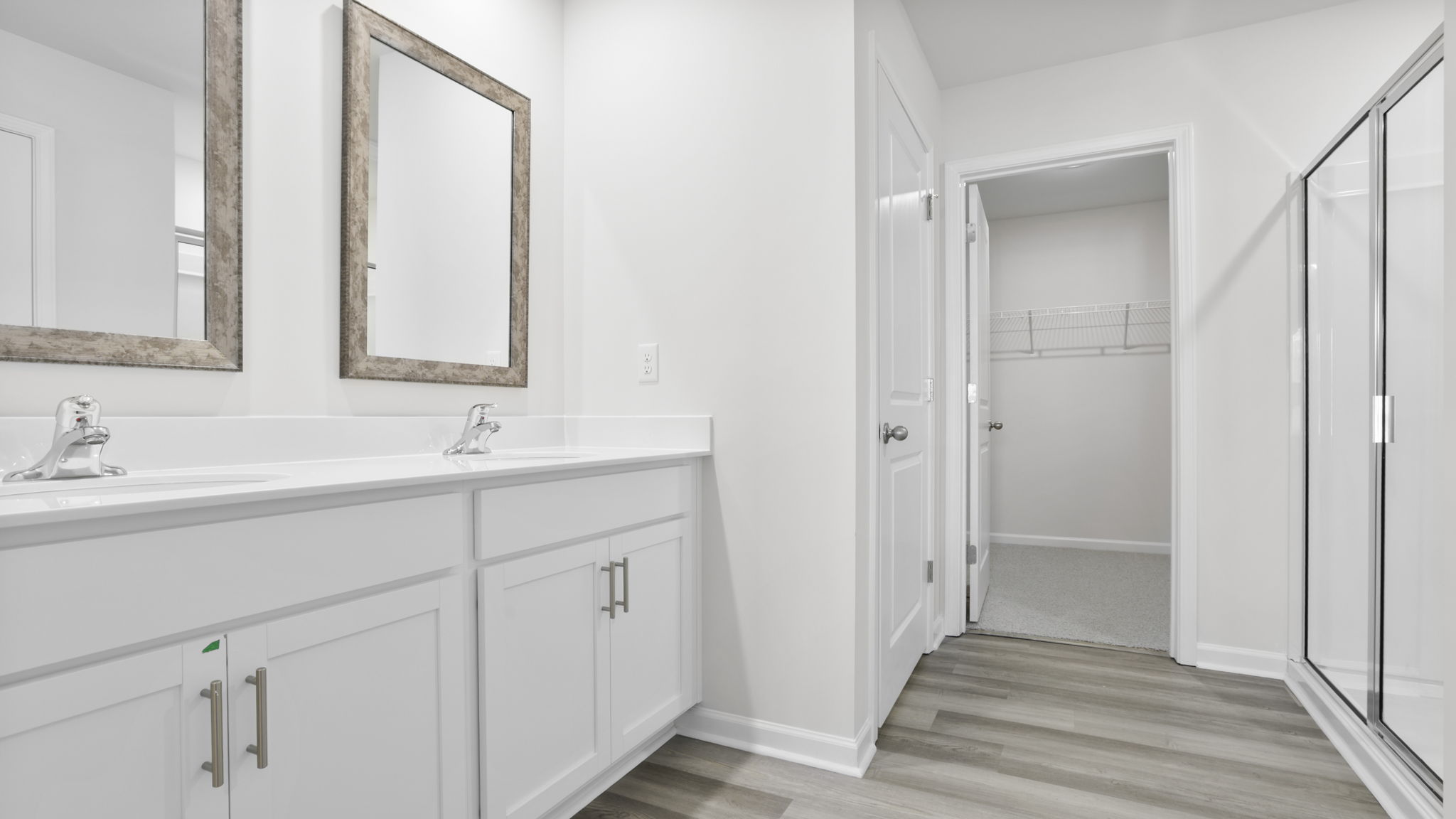 Primary bathroom with double sink vanity and walk in closet.