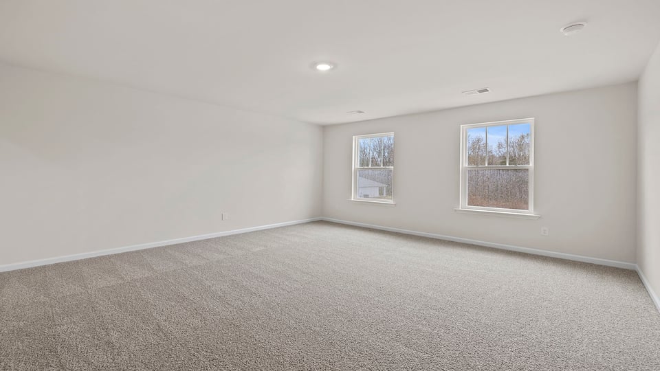 Primary bedroom with large windows and carpet.