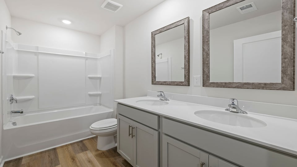Hall bathroom with dual sink vanity and combination shower / tub.