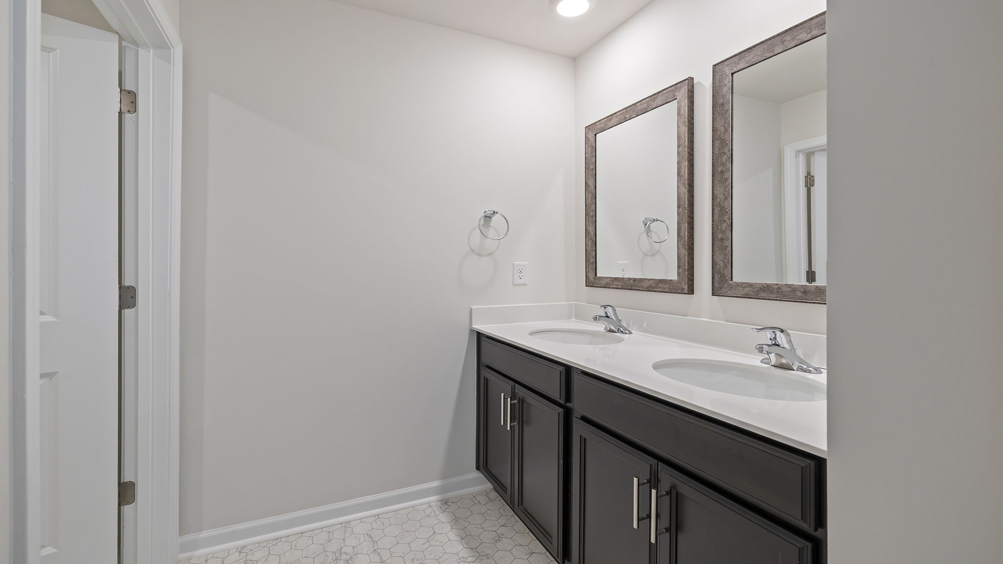 Hall bathroom with dual sink vanity and mirrors.
