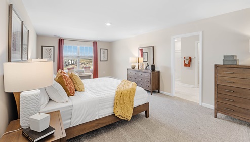Primary bedroom with carpet and window.