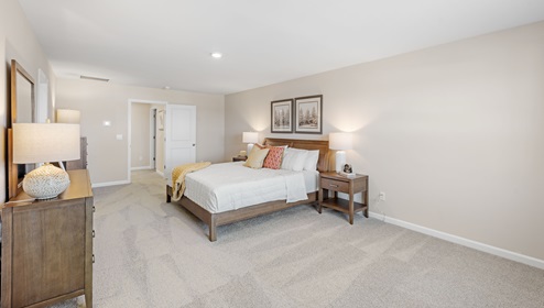 Primary bedroom with carpet and window.