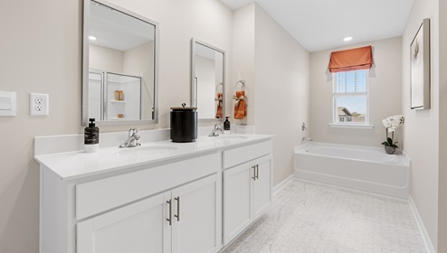 Primary bathroom with double vanity sinks and window.