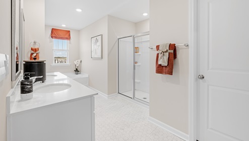 Primary bathroom with double vanity sinks and window.