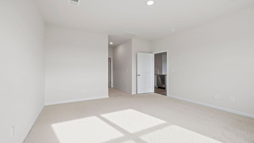 Primary bedroom with carpet and window.